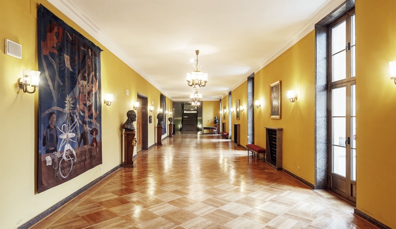 Wnętrze foyer, po lewej stronie ściana z gobelinami i popiersiami kompozytorów, po prawej stronie okna