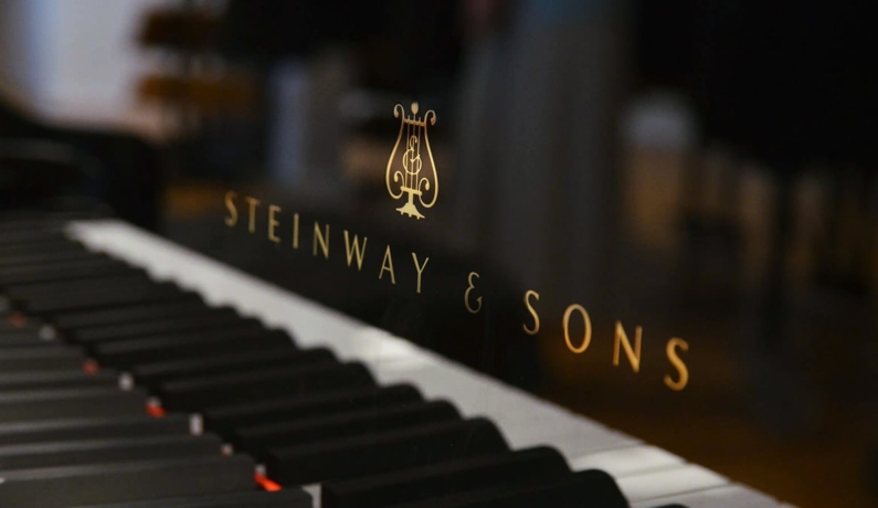 Klawisze fortepianu, nad nimi widnieje napis marki – Steinway & Sons