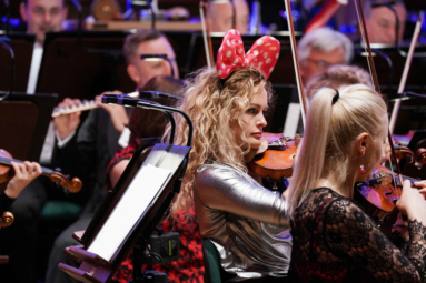 zdjęcie skrzypaczki w uszach Mickie Mouse, grającej koncert dla dzieci z