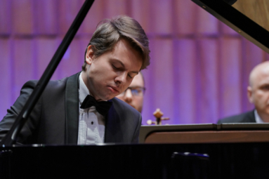 zdjęcie młodego pianisty w smokingu, grającego na fortepianie