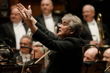 zdjęcie dyrygenta wskazującego z uśmiechem na orkiestre
