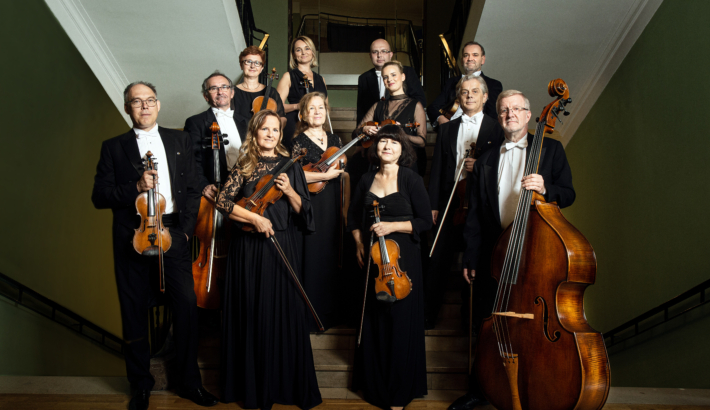 muzycy orkiestry kameralnej capella bydgostiensis pozujący do zdjęcia z instrumentami
