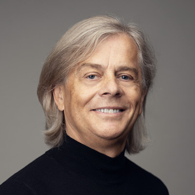 zdjęcie portretowe uśmiechniętego mężczyzny w średnim wieku z długimi jasnymi włosami