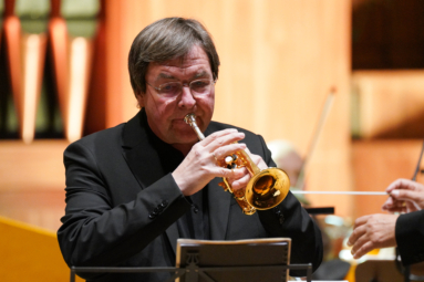 mężczyzna w średnim wieku grający na trąbce