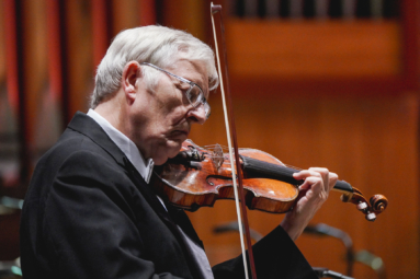 zdjęcie straszego siwego mężczyzny w okularach, grającego na skrzypcach