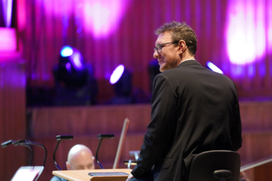 zdjęcie dyrygenta uśmiechającego się do orkiestry