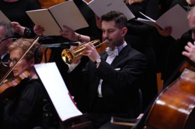 zdjęcie trębacza ubranego w elegancki frak, grającego na trąbce