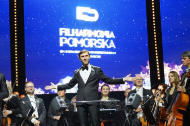 Zdjęcie dyrygenta i orkiestry odwróconych w stronę publiczności