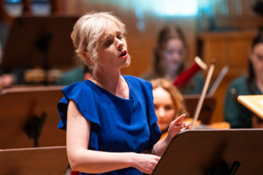 młoda śpiewaczka w blond włosach i sukience w intensywnym, niebieskim kolorze